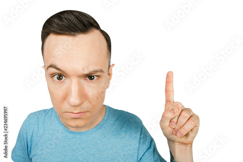 Portrait of young morose guy showing index finger up isolated on a white background.