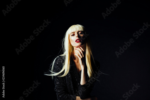 Sensual portrait of a beautiful blonde woman with red lips and nails, isolated on black studio background