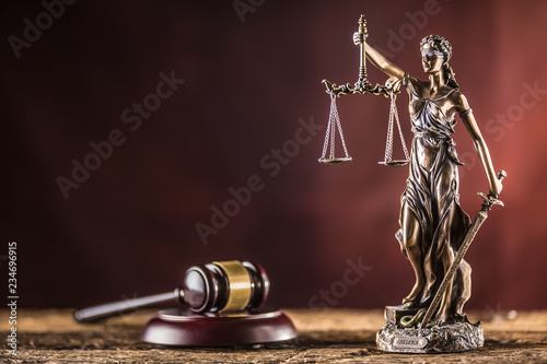 Lady Justicia holding sword and scale bronze figurine with judge hammer on wooden table photo