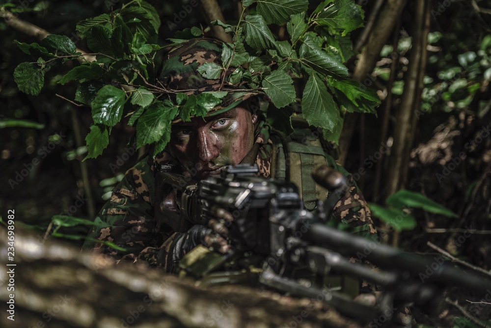 Portrait of a camouflaged soldier in forest during patrol