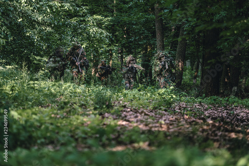 Camouflaged soldiers in forest during summer on patrol	