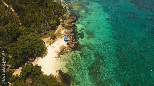 Aerial view of tropical beach on the island Bohol, Anda area, Philippines. Beautiful tropical island with sand beach, palm trees. Tropical landscape: beach with palm trees. Seascape: Ocean, sky, sea