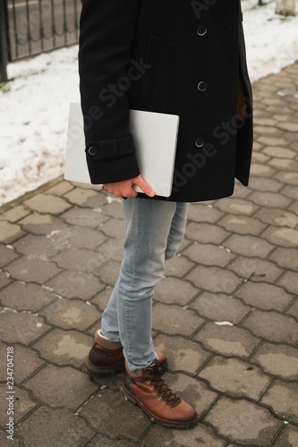 young hipster man with laptop in hand with a urban look in city. in the city winter