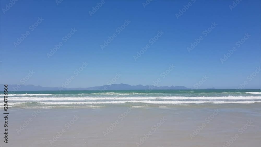 Waves rushing towards the beach Mountains in Background Waves rushing towards the beach Mountains in Background