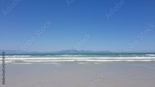 Waves rushing towards the beach Mountains in Background