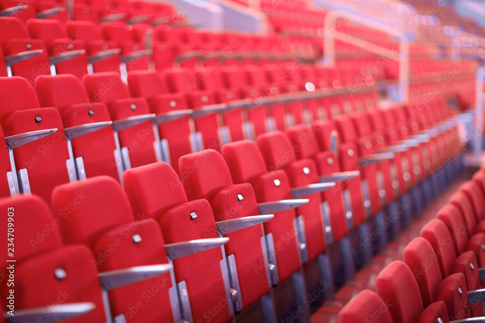Fototapeta premium Rows of red numbered seats with armrests in a large auditorium