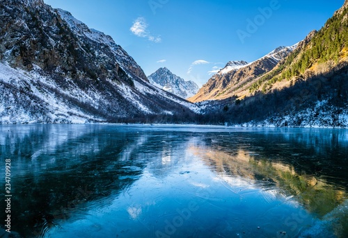 Panoramic landscape, frozen mountain Baduk lake and mountain range with reflection on ice, national park in Caucasus mountains, Russia © VarnakovR