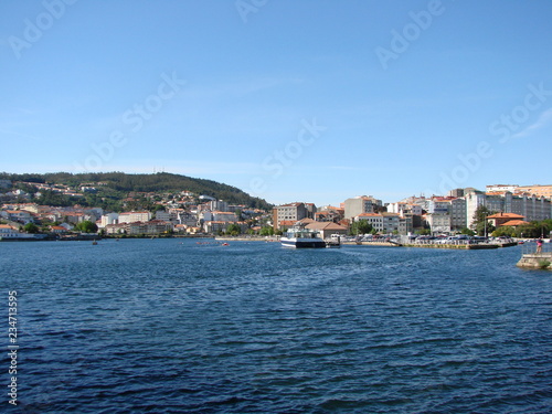 Panorama of the inhabited coastal strip of a small town on the background of blue colors of the water surface of the river and the evening sky. © Hennadii