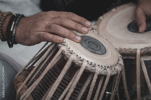 Canvastavla Images of a man's hands (wearing beads) playing the Tabla - Indian classical music percussion instrument - black background