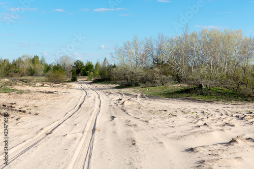  The road among the sands on a background of blue sky in early spring