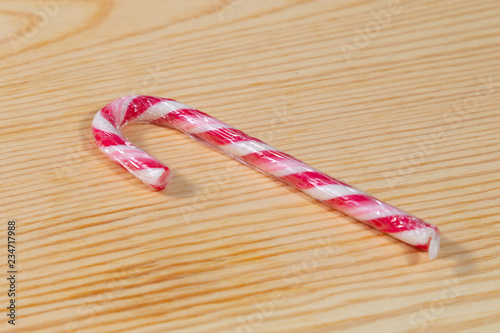 Single red candy cane on wooden background