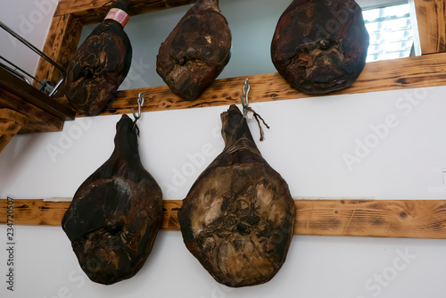 Smoked pork legs hanging on hooks. The national dish of Italy, Spain or the Balkans. photo