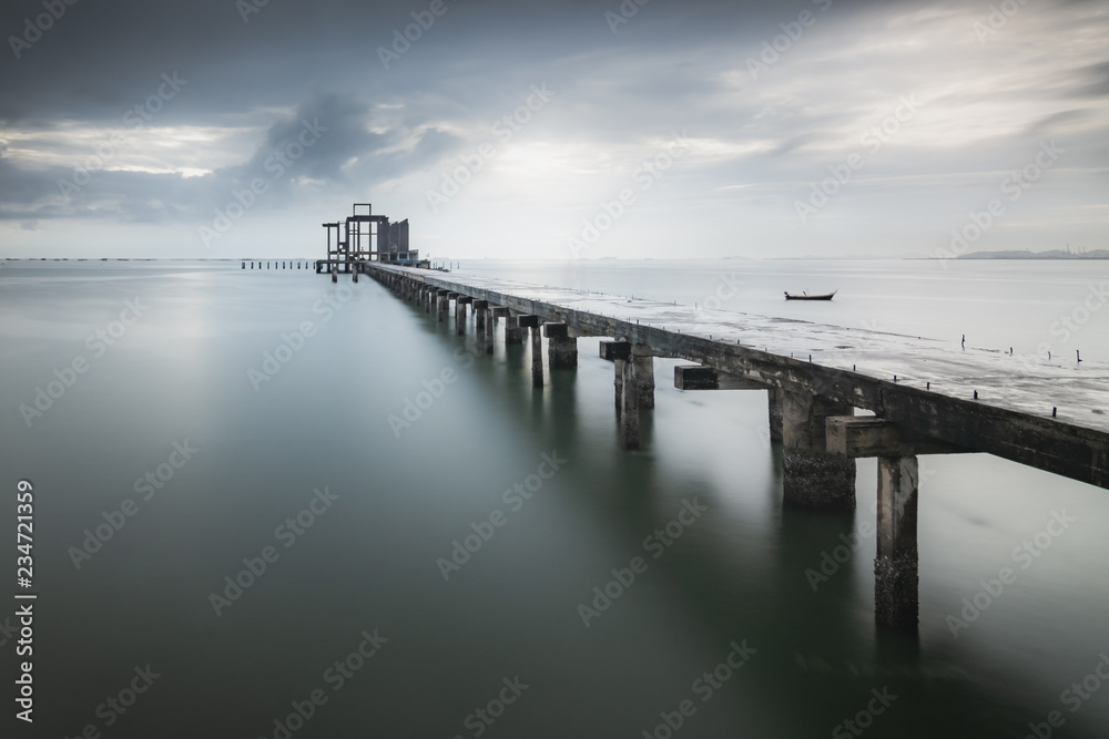 Nature background of a long bridge over an ocean with calm waves and water under blue clouds and sky in the morning