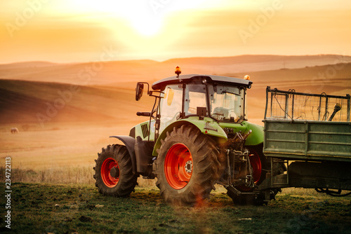 Details of farmer working in the fields with tractor on a sunset background. Agriculture industry details photo