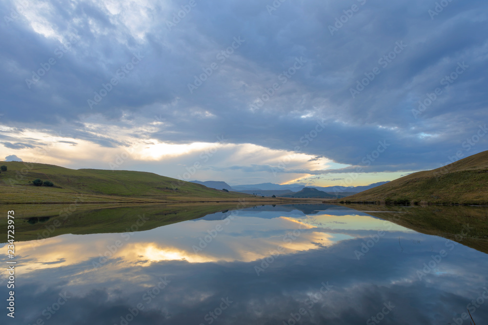 Obraz premium Clouds reflect on the water at sunset