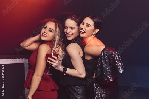 Beautiful elegantly dressed female friends have fun at the nightclub