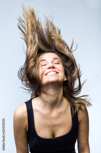 Cute smiling woman with beautiful long flying hair over white background. Healthy hair, haircare.