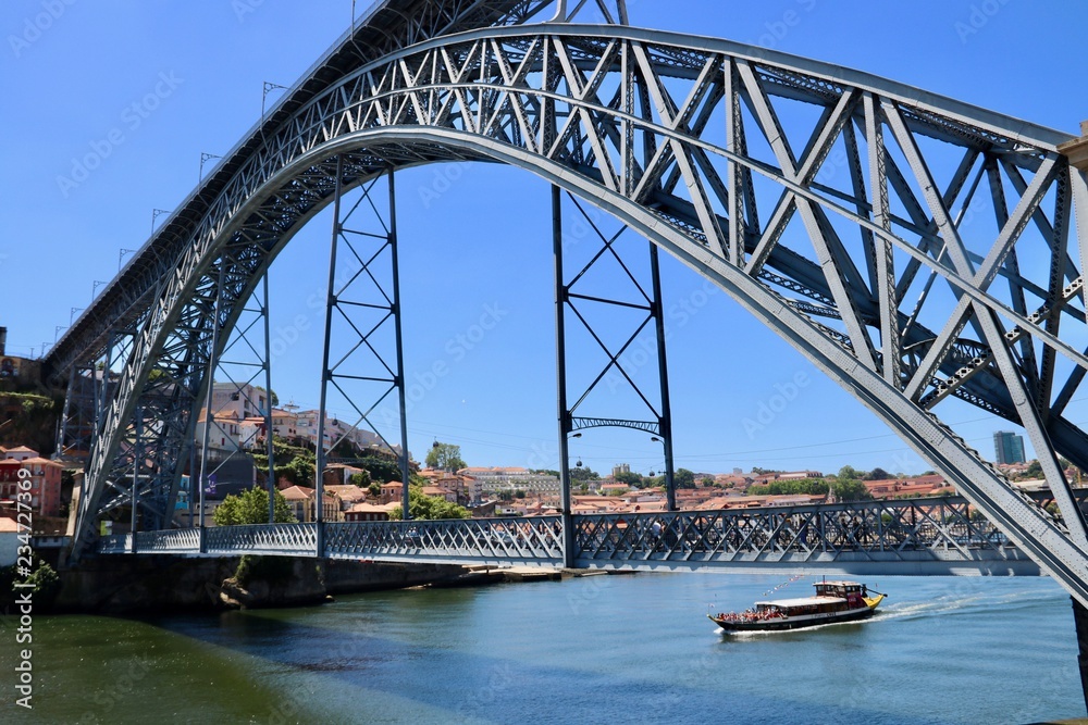 Naklejka premium Boat passing under Dom Luis Bridge