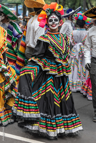 Colorful participants in the festival of the Day of the dead in Mexico. Attractive skull costumes worn by dancing Mexican girls