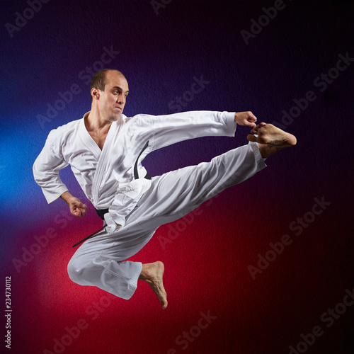 The athlete beats a kick in the jump on a red and blue background
