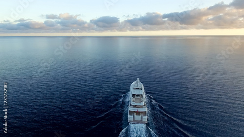 A stunning aerial view of large super yacht underway on the sunset