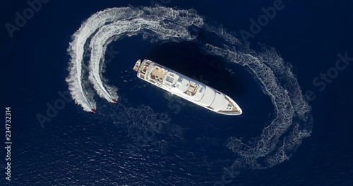 Aerial view of two jet-ski moving around large yacht