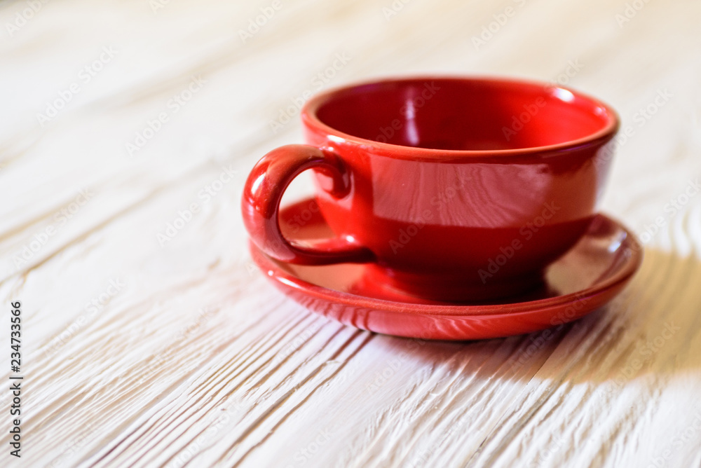 Obraz premium a red mug with a saucer on a white wooden background.