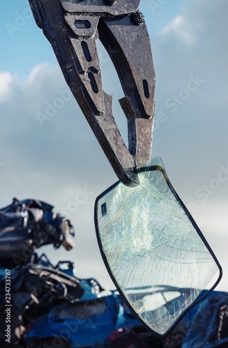 crane holds broken windscreen on scrapyard