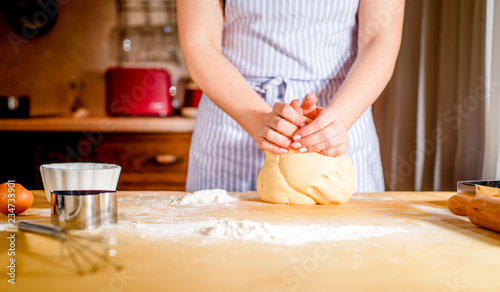 women's hands knead the dough on the table, kitchen accessories