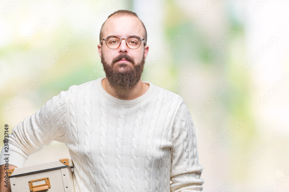 Young hipster man wearing glasses, moving holding moving box over isolated background with a confident expression on smart face thinking serious Young hipster man wearing glasses, moving holding moving box over isolated background with a confident expression on smart face thinking serious