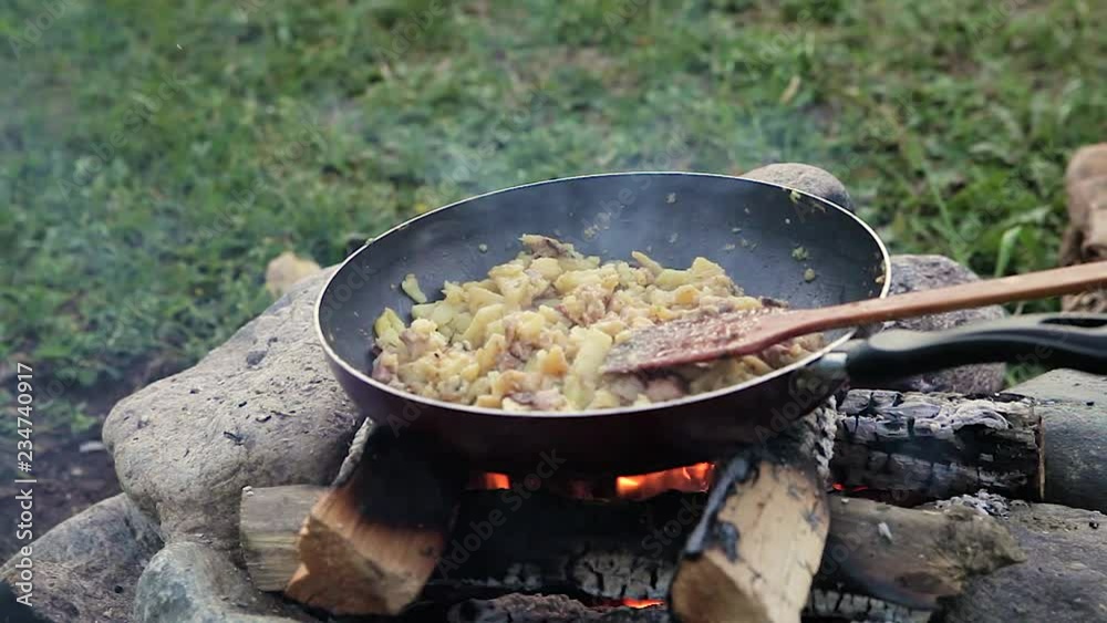 summer day / evening. tourist vacation in the journey. cooking on the fire in a frying pan, the fire is made of stones. the fire is burning on the wood. summer day / evening. tourist vacation in the journey. cooking on the fire in a frying pan, the fire is made of stones. the fire is burning on the wood.