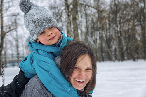 Mom and little son playing in the snow in winter