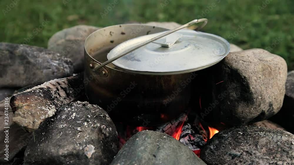 summer day / evening. tourist vacation in the journey. cooked ear in a pot on the fire, the fire is made of stones. the fire is burning on the wood. summer day / evening. tourist vacation in the journey. cooked ear in a pot on the fire, the fire is made of stones. the fire is burning on the wood.