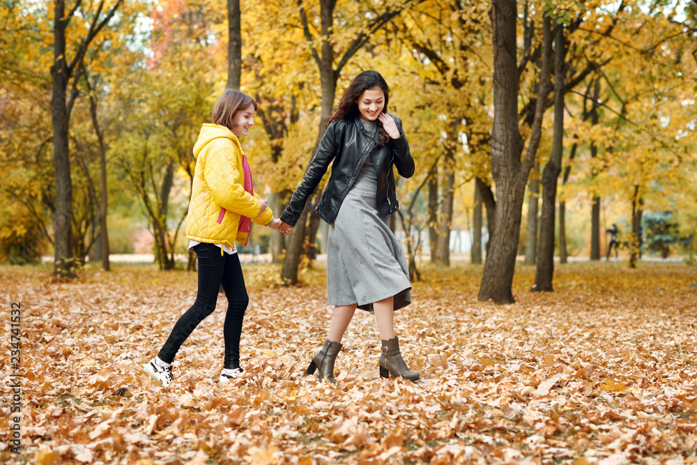Obraz premium Two happy girls running in autumn city park.