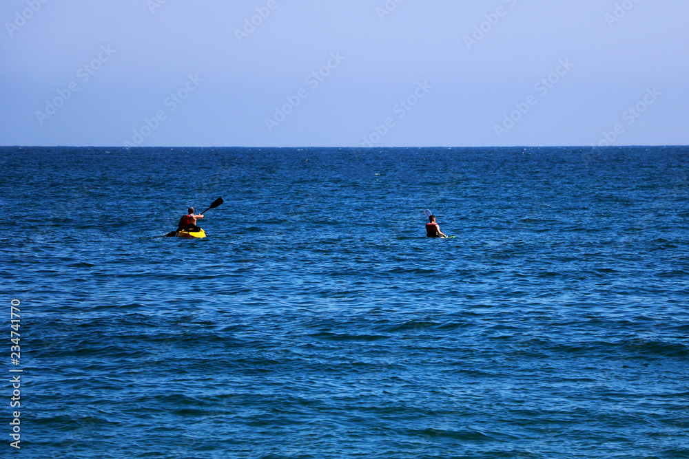 A couple of friends canoeing on a wooden canoe on a sunny day. USA.