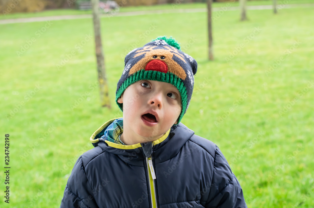 Defect,childcare,medicine and people concept- young boy with a down syndrome who is playing in a park. Defect,childcare,medicine and people concept- young boy with a down syndrome who is playing in a park.