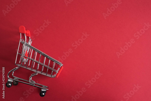 Close-up of empty shopping trolley cart on red background with copy space 