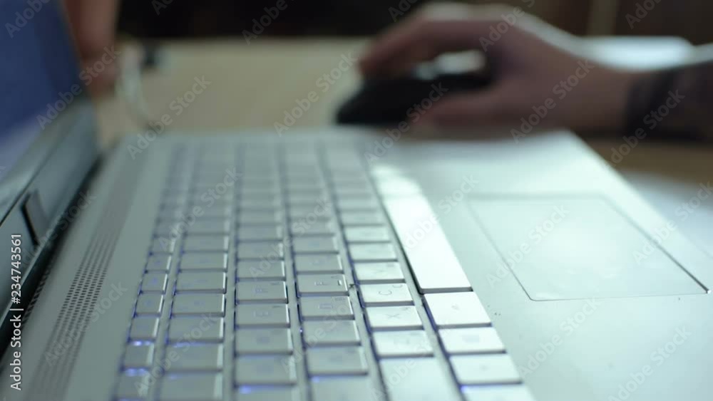 The girl uses the computer. Records on the keyboard. wireless computer mouse on a white table. Close-up. The girl uses the computer. Records on the keyboard. wireless computer mouse on a white table. Close-up.