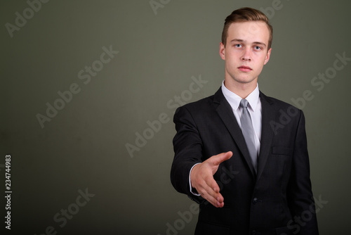 Young handsome businessman wearing suit against colored backgrou