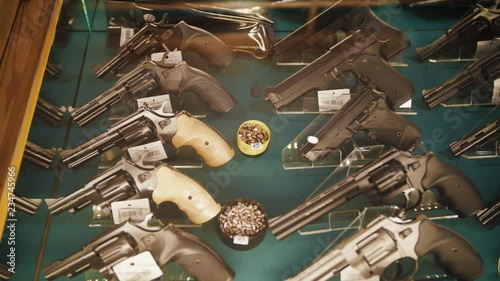Different guns and revolvers on shelves store weapons on shop center.