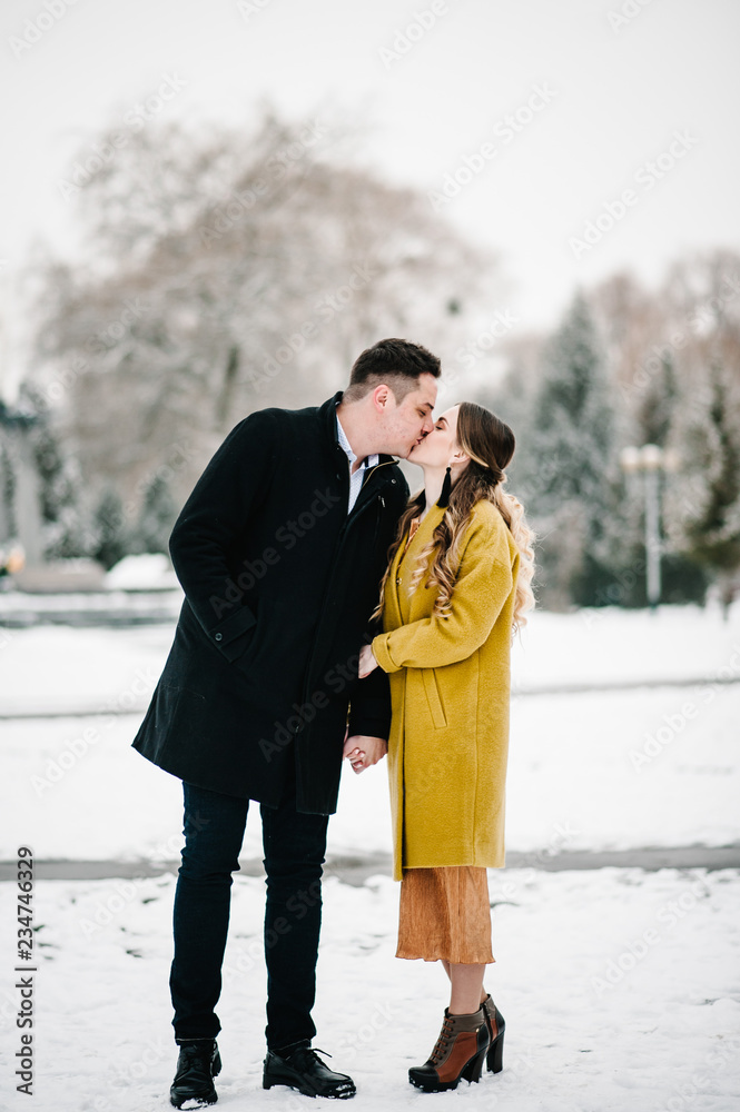 Happy couple enjoying, hugging and kiss near christmas tree, outdoors in winter. Man and woman, season, love and leisure concept. Happy couple enjoying, hugging and kiss near christmas tree, outdoors in winter. Man and woman, season, love and leisure concept.