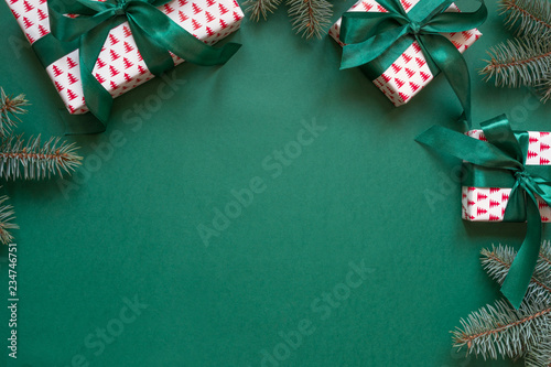 Christmas gift boxes and evegreen branches on green. Invitation. Space for wishes. Top view.