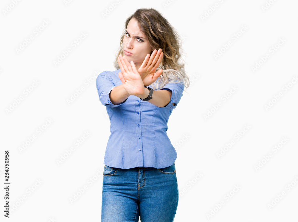 Beautiful young blonde business woman over isolated background Rejection expression crossing arms and palms doing negative sign, angry face Beautiful young blonde business woman over isolated background Rejection expression crossing arms and palms doing negative sign, angry face