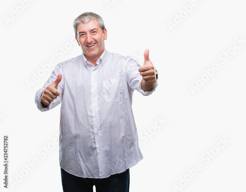 Handsome senior man over isolated background approving doing positive gesture with hand, thumbs up smiling and happy for success. Looking at the camera, winner gesture.