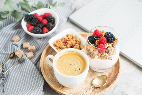 Healthy Breakfast Cup of Coffee Greek Yogurt with Homemade Granola, Berries, Raspberries and Blackberries Work Laptop Morning Concept