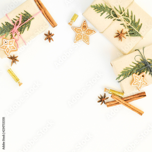 Cozy holiday background in warm, trendy colorsand white. Christmas composition of spruce branches, gift, gingerbread cookies, cinnamon, anise and confetti in small jars. Flat lay, top view photo