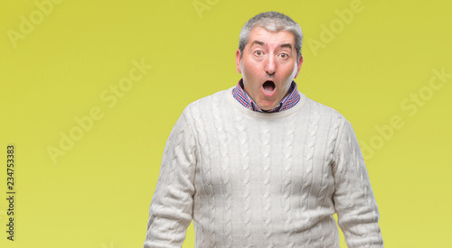 Handsome senior man wearing winter sweater over isolated background afraid and shocked with surprise expression, fear and excited face. © Krakenimages.com