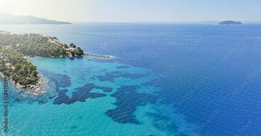 Drone aerial view of sea shore on stones and blue water