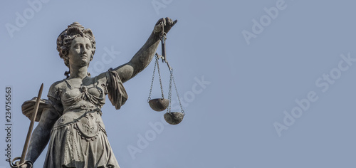 Statue a judge woman with scales and sword at smooth blue background in Frankfurt, Germany, details, closeup