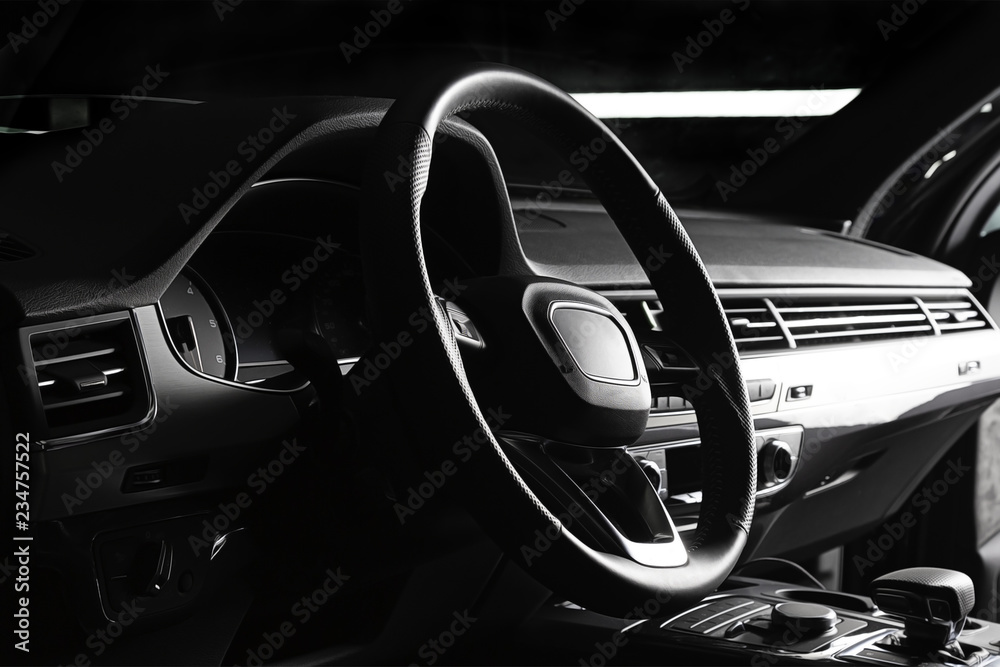 Modern luxury prestige car interior, dashboard, steering wheel. Black leather interior.